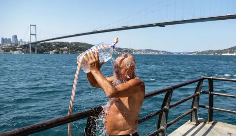 epa11491470 A man pours water on his head to cool off in front of the 15 July Martyrs Bridge during heatwave in Istanbul, Turkey, 22 July 2024. AKOM, the Istanbul Disaster Coordination Center announced that the temperature will reach 36 degrees in Istanbul on 22 July, due to a heat wave originating from Africa and Basra. EPA/ERDEM SAHIN