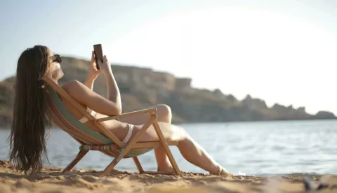 žena surfa na mobitelu, plaža