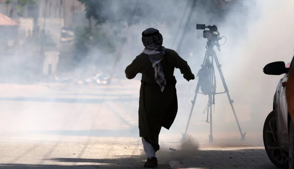 epa11521172 A man kicks a tear gas canister fired during an Israeli raid at Tulkarem refugee camp in the West Bank city of Tulkarem, 03 August 2024. At least four Palestinians inside a car were killed on 03 August following an Israeli airstrike in Zeta village, near Tulkarem, according to the Palestinian Health Ministry. EPA/ALAA BADARNEH