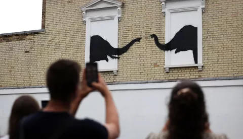 epa11530751 People view a new artwork by British anonymous street artist Banksy depicting two elephants in Chelsea, London, Britain, 06 August 2024. It is the second artwork Banksy has released on his official website in two days. EPA/ANDY RAIN