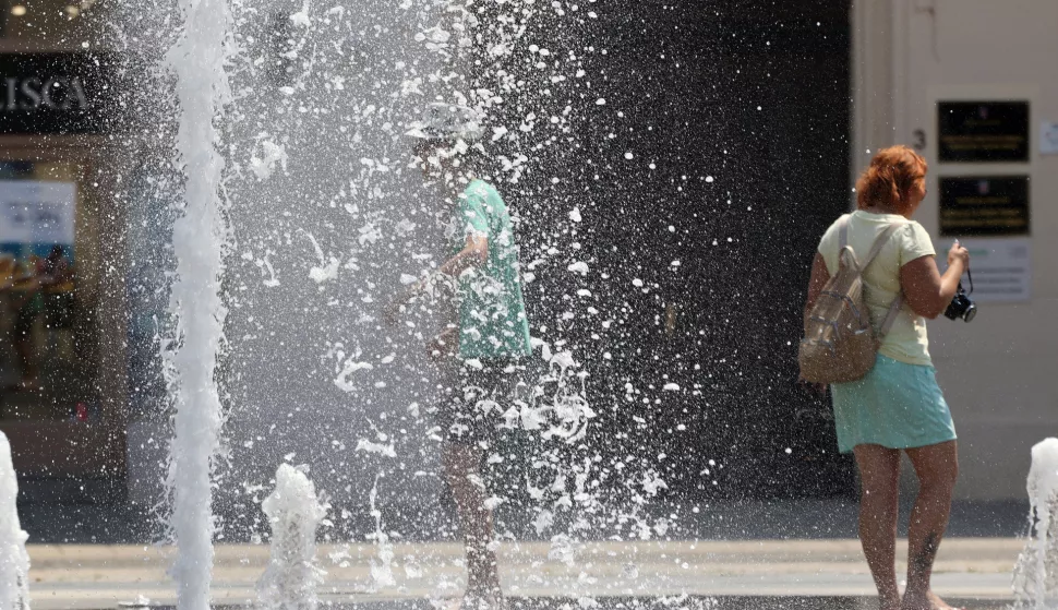 Osijek, 12. 07. 2024, Trg Ante Starcevica, fontana, turisti se osvjezavaju u fontani. Oko 14 sati temperatura u Osijeku je bila 38,8 C tako je pokazivao led displej na obali Drave u Zimskoj luci. Ljudi se snalaze na razne nacine kako bi se zastitili od vrucine i sunca. snimio GOJKO MITIĆ