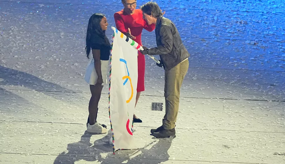 12 August 2024, France, Paris: Olympia, Paris 2024, Stade de France, US actor Tom Cruise receives the Olympic flag from Simone Biles. In the center is Mayor of Los Angeles Karen Bass. Photo: Michael Kappeler/dpa Photo: Michael Kappeler/DPA