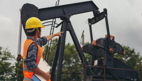 Workers standing and checking beside working oil pumps.nafta plin energijafreepik