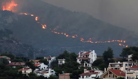 epa11546309 A fire approaches houses at Penteli mount, northeast Attica, Greece, 12 August 2024. Despite efforts by civil protection forces throughout the night, the fire raging in northeast Attica had advanced rapidly and was moving in the direction of Penteli, having spread over the Penteli mountain range. Authorities evacuated the Penteli Children's Hospital and the 414 Military Hospital in the area. EPA/GEORGE VITSARAS