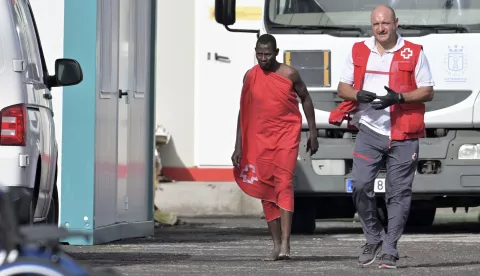 epa11557747 A migrant carries a red blanket while being accompanied by a member of the Red Cross in the port of La Restinga, in the municipality of El Pinar, Canary Islands, Spain, 21 August 2024. Sixty-one migrants were rescued at sea off El Hierro by a Salvamento Maritimo boat and transferred to the port of La Restinga. EPA/GELMERT FINOL