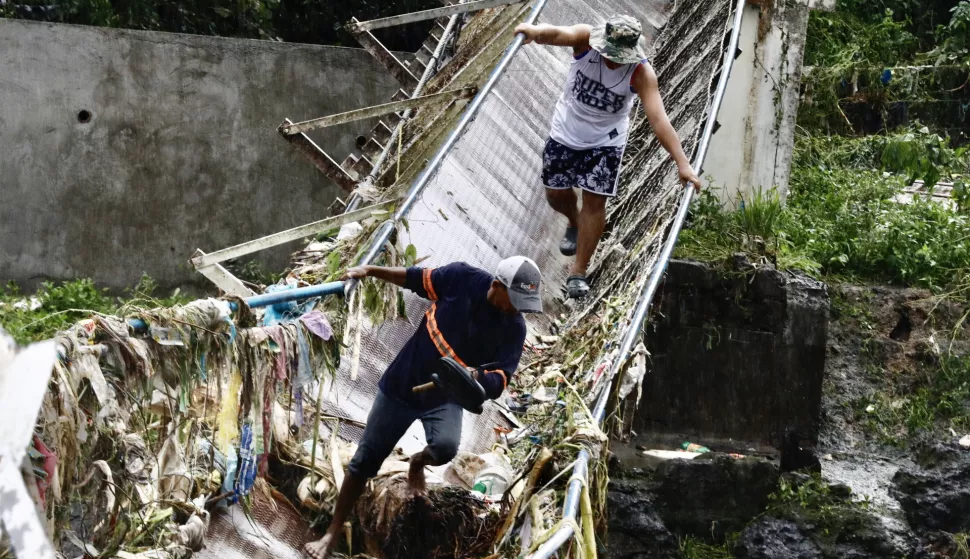 epaselect epa11581116 Villagers try to cross a flood-hit bridge in Teresa, Rizal province, about 50 kilometers east of Manila, Philippines, 03 September 2024. In a 03 September report by the National Disaster Risk Reduction and Management Council (NDRRMC), ten people have died, ten have been injured, and thousands of residents left their homes due to flooding in the wake of Typhoon Yagi. EPA/FRANCIS R. MALASIG