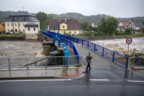 epa11603533 A local man walks during heavy rain near the overflowing Bela river in Mikulovice, Czech Republic, 14 September 2024. The Czech Hydrometeorological Institute (CHMU) has issued a extreme precipitation warning of unusually intense rainfall which can significantly raise water levels and that will affect the Czech Republic from 12 September until the end of the week. EPA/MARTIN DIVISEK