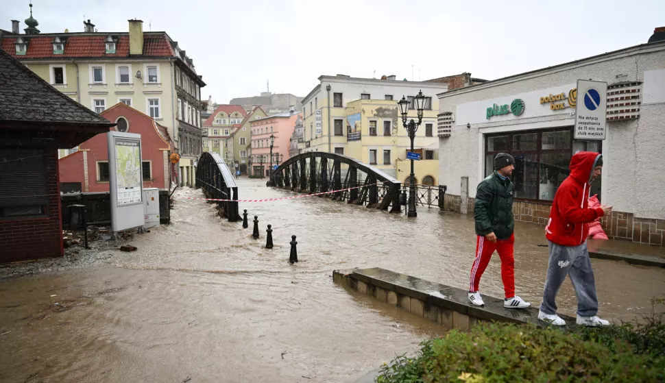 epa11605256 People pass by next to a flooded street after the heavy rainfalls caused the flooding in Klodzko, southwestern Poland, 15 September 2024. The next 24-36 hours will be crucial for the southern regions of Poland experiencing record downpours. On 14 September, the Institute of Meteorology and Water Management (IMGW) reported that the water level exceeded the alarm condition at 41 hydrological stations and the warning condition at 30 stations. EPA/Maciej Kulczynski POLAND OUT