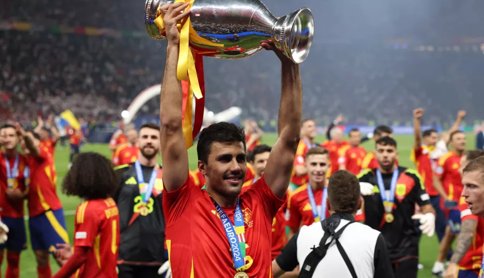 epa11478963 Rodri of Spain celebrates with the trophy after winning the UEFA EURO 2024 final soccer match between Spain and England, in Berlin, Germany, 14 July 2024. EPA/CHRISTOPHER NEUNDORF