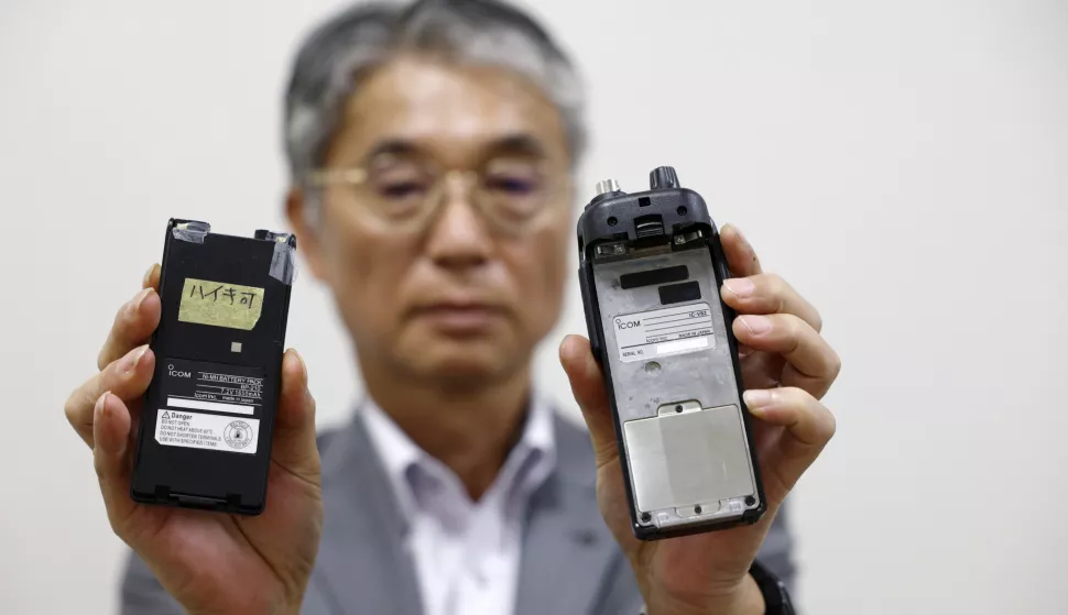 epa11613244 Japanese walkie-talkie maker Icom Inc. director Yoshiki Enomoto shows its radio model IC-V82 device and its battery (L) at the company head office in Osaka, western Japan, 19 September 2024. Japanese firm Icom Inc. announced on its website on 19 September that it was investigating reports that device with the company logo exploded in Lebanon. The company stated that the IC-V82 radio model, reportedly involved in the recent blasts, was discontinued around 10 years ago. EPA/FRANCK ROBICHON