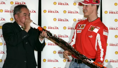 epa000380591 German formula one driver Michael Schumacher (R) of Ferrari looks at Jhon So, the mayor of Melbourne, who plays a didgeridoo following a press conference, Wednesday 02 March 2005 in Melbourne, Australia. The first Grand Prix of the season 2005 will start on Sunday 06 March 2005. EPA/Gero Breloer