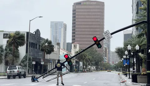 epa10213733 A man walks on Orange Avenue amidst downed traffic lights following Hurricane Ian, in Orlando, Florida, USA, 29 September 2022. Hurricane Ian came ashore as Category 4 hurricane according to the National Hurricane Center and is nearing an exit into the Atlantic Ocean on the East Coast of Florida. EPA/GARY BOGDON