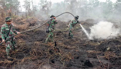 epa07841054 Indonesian military personnel spray water on burning peat land in Pekanbaru, Riau province, Indonesia, 14 September 2019. According to media reports, firefighters, military personnel and water-bombing helicopters have been deployed to douse intense forest fires in Sumatra and Borneo that may impact neighboring countries (Singapore, Malaysia and Thailand) with smoke. EPA/STRINGER