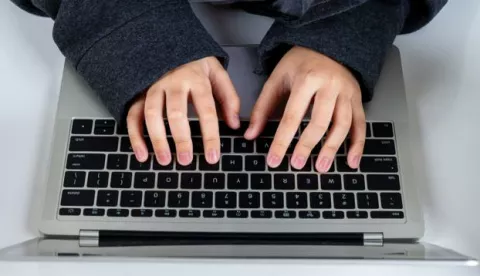 Top view and close up Asian hacker boy typing on laptop computer keyboard on with background