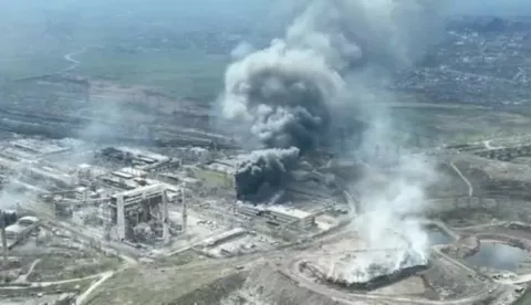 epa09896967 A frame grab from an undated handout drone video first published by DPR militia commander Alexander Khodakovsky and made available by the Mariupol City Council shows smoke rising from the Azovstal steel plant during airstrikes in Mariupol, eastern Ukraine, 18 April (issued 19 April 2022). The Russian Defence Ministry on 19 April 2022 issued a statement calling on the Ukrainian forces in Mariupol "to cease any hostilities and lay down their arms. All who lay down their weapons are guaranteed the preservation of life." The city council on 18 April 2022 via their official Telegram channel said that at least 1,000 civilians are sheltering in the underground shelters of the metallurgical plant, and that heavy bombs were dropped on the Azovstal plant by Russian forces. EPA/MARIUPOL CITY COUNCIL HANDOUT HANDOUT EDITORIAL USE ONLY/NO SALES