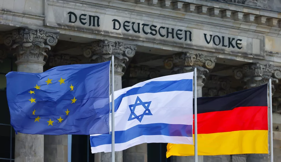 epa10912832 An Israeli flag flutters between a German and an EU flag before a minute of silence for the Israeli victims of the deadly attacks by the Palestinian militant group Hamas, during a debate at the German parliament Bundestag in Berlin, Germany, 11 October 2023. EPA/HANNIBAL HANSCHKE