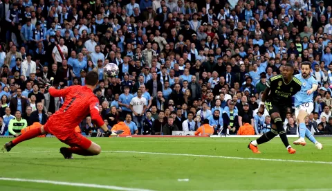 epa10634967 Bernardo Silva (R) of Manchester City scores the opening goal against Real Madrid goalkeeper Thibaut Courtois during the UEFA Champions League semi-finals, 2nd leg soccer match between Manchester City and Real Madrid in Manchester, Britain, 17 May 2023. EPA/DAVID RAWCLIFFE