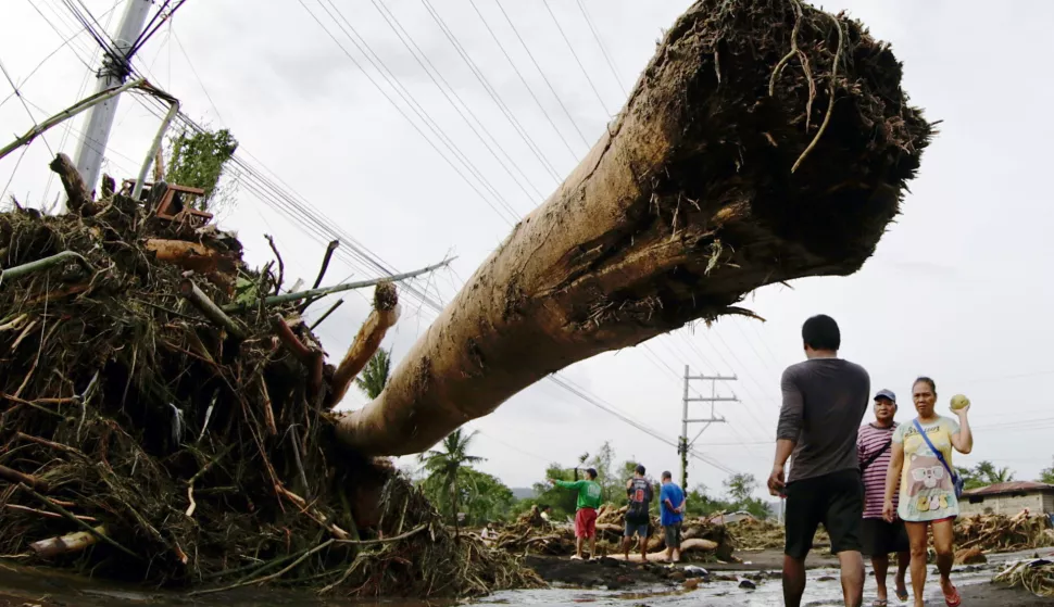 epa11681964 Villagers walk past a washed up log in the flood-hit town of Laurel, Batangas province, Philippines, 25 October 2024. At least 30 people were killed and more than 200,000 villagers fled their homes as Tropical Storm Trami barreled the Philippines, officials said on October 25. Trami dumped heavy rain, triggering widespread flooding and landslides. EPA/FRANCIS R. MALASIG