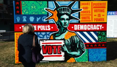 epa11690600 A woman passes signs encouraging early voting near Philadelphia City Hall in Philadelphia, Pennsylvania, USA, 29 October 2024. EPA/WILL OLIVER