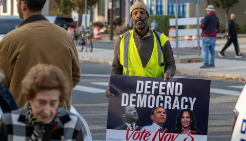 epa11701633 A man walks through the crowd holding a sign that reads 'Defend Democracy' in Philadelphia, Pennsylvania, on 04 November 2024. US Vice President and Democratic Presidential Nominee Kamala Harris is holding an election eve concert and rally in Philadelphia. Election polls show that the presidential race between Harris and Republican nominee former President Donald Trump is extremely close. EPA/DAVID MUSE