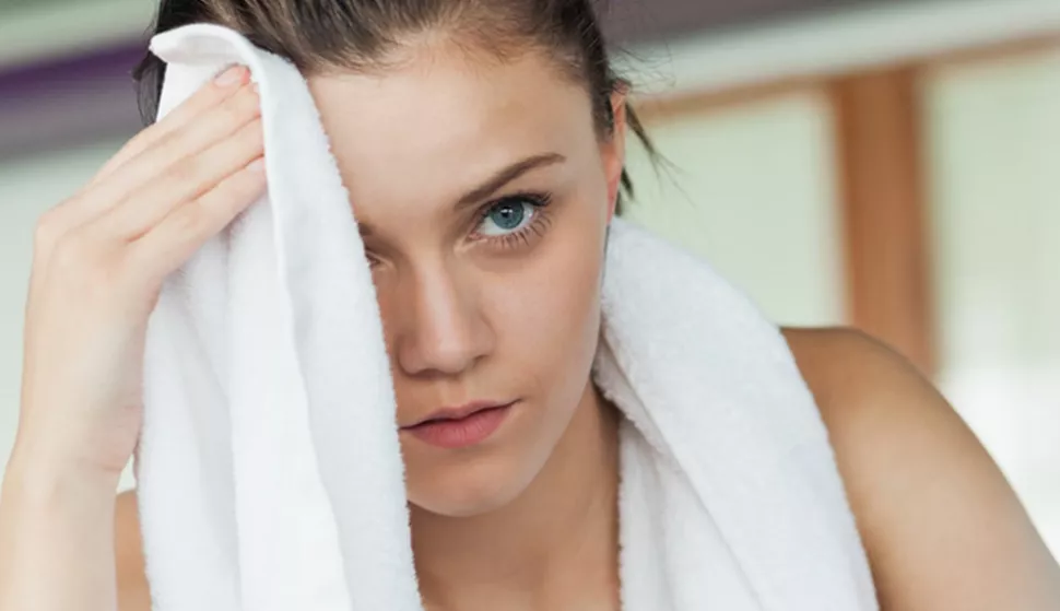 Tired young woman wiping face while working on row machine in fitness studio; Shutterstock ID 161499752; PO: today.com mish
