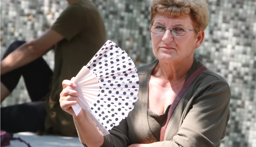 Osijek, 12.08.2020. - Dok gospođa čeka u hladovini ipak dobro dođe lepeza da se malo rashladi.koronavirus; COVID-19FOTO: Željko &Scaron;epić