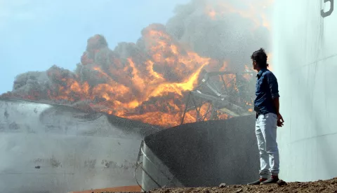 epa07277031 A Yemeni looks on as fire ignites in an oil storage tank at the main oil refinery in the southern port city of Aden, Yemen, 12 January 2019. According to reports, a massive fire engulfed an oil storage tank holding 7,000 tonnes of diesel at the main oil refinery in the southern Yemeni port city of Aden, causing a lot of damage. The impact of the fire on the whole refinery is still not known. EPA/NAJEEB ALMAHBOOBI