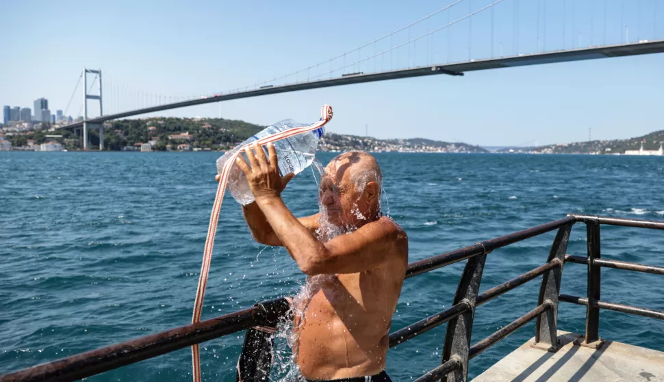 epa11491470 A man pours water on his head to cool off in front of the 15 July Martyrs Bridge during heatwave in Istanbul, Turkey, 22 July 2024. AKOM, the Istanbul Disaster Coordination Center announced that the temperature will reach 36 degrees in Istanbul on 22 July, due to a heat wave originating from Africa and Basra. EPA/ERDEM SAHIN