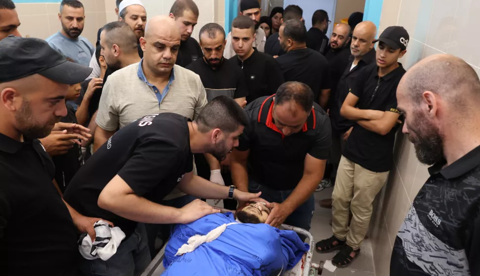 epa11454248 People mourn next to the body of a Palestinian man killed during an Israeli military strike, in the hospital of Tulkarem, West Bank, 03 July 2024. At least four people were killed in an Israeli airstrike at Nour Shams camp, near the West Bank city of Tulkarem, according to the Palestinian Ministry of Health. EPA/ALAA BADARNEH