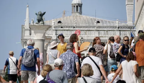 epa11515174 A tour guide (C), using a radio microphone to communicate, leads a group of visitors to St. Mark's Square, in Venice, Italy, 01 August 2024. Venice's city administration from 01 August will start enforcing new rules that limit tourist groups' sizes to 25 people and prohibit the use of loudspeakers by tour guides, seeking to reduce the impact of over-tourism on the city's residents. EPA/ANDREA MEROLA