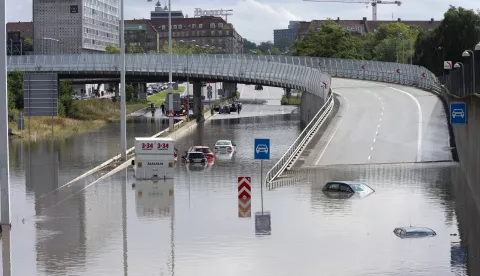 epa11526036 Rescuers stand next to submerged vehicles at a water-logged road after heavy rain on Lyngbyvejen in Copenhagen, Denmark, 04 August 2024. The heavy rain caused traffic problems in several places in the capital area. EPA/THOMAS SJOERUP DENMARK OUT