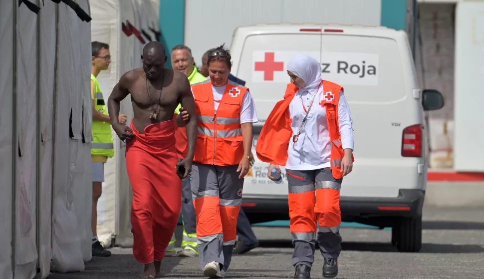 epa11547757 Red Cross members attend a man who arrived in a 'cayuco' (small wooden boat) within a group of 97 migrants at the port of La Restinga, in El Hierro, Canary Islands, Spain, 13 August 2024. EPA/GELMERT FINOL