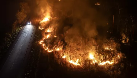 epa11601460 A picture taken with a drone shows a car driving along the BR-364 highway in an area engulfed by a forest fire near the city of Porto Velho, Rondonia state, Brazil, late 12 September 2024 (issued 13 September 2024). The destruction caused by fires in August 2024, with 5.6 million hectares burned, represents 49 percent of the entire surface area devastated by flames in the country since the beginning of this year, according to data released by scientific platform MapBiomas. EPA/ISAAC FONTANA