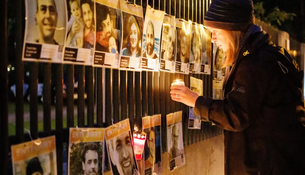 epa11646288 Martina holds a candle with the name of an Israeli hostage in her hand, as she stands in front of portraits of Isreali hostages in front of the Synagogue at the Fraenkelufer in Berlin, Germany, 06 October 2024. The vigil took place under the motto 'We stand by your side, vigil to protect Jewish life'. Upcoming 07 October 2024 marks one year since the Palestinian militant group Hamas launched a surprise attack on Israel, killing 1,200, and one year since Israel began its war on Gaza, killing more than 41,000 and destroying the Palestinian enclave. EPA/CLEMENS BILAN