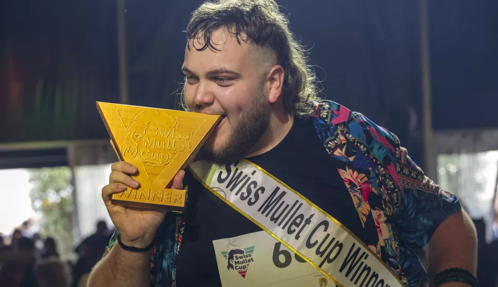 epa11645798 Kilian Wicht winner of the Swiss Mullet Cup celebrates with the trophy, during a special event designed to celebrate the mullet hairstyle in which the hair is cut shorter at the front, top and sides, but is longer at the back, at the Foire du Valais in Martigny, Switzerland, 06 October 2024. EPA/SALVATORE DI NOLFI