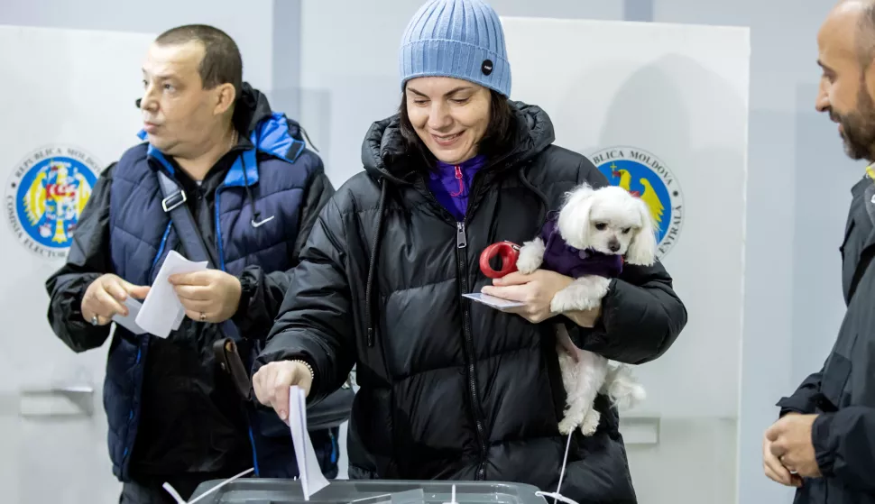 epa11670479 A woman holding her dog casts her ballot at poling stations in Chisinau, Moldova, 20 October 2024. Moldova holds presidential election and a referendum on whether to enshrine in the Constitution the country's path to EU membership on 20 October. EPA/DUMITRU DORU