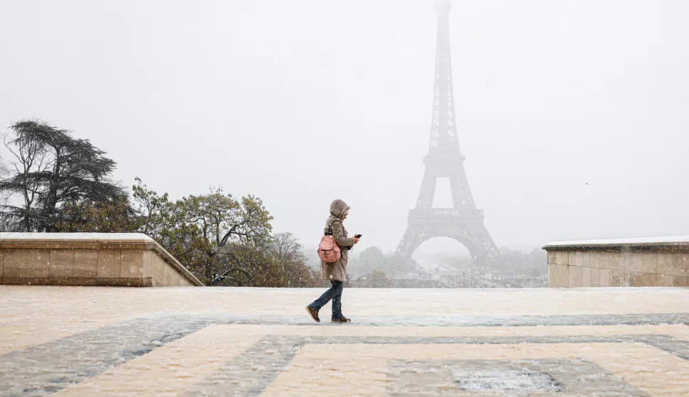 epa11733282 A woman walks during snowfall near the Eiffel Tower in Paris, France, 21 November 2024. French National Weather and Climate Service Meteo-France issued an 'orange' warning in 32 departments from northern Brittany and Normandy to the Ile-de-France due to snowfall and freezing rain forecasted on 21 November. EPA/MOHAMMED BADRA