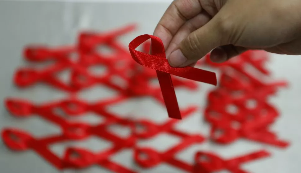 epa05049290 A Taiwanese picks a red ribbon inside the Centers for Disease Control (CDC) building on the eve of World AIDS Day in Taipei, Taiwan, 30 November 2015. World AIDS Day is marked worldwide annually on 01 December to raise awareness for those living with the virus. EPA/RITCHIE B. TONGO