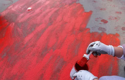 epa11751317 A protestor paints the pavement with red paint symbolizing blood during the one month anniversary of the Novi Sad train station accident in Novi Sad, Serbia, 01 December 2024. Fifteen people lost their lives in the collapse of the Novi Sad Railway Station canopy on 01 November 2024. The station building, which had been renovated and reopened on 05 July 2024, was undergoing further renovations shortly before the collapse. EPA/ANDREJ CUKIC