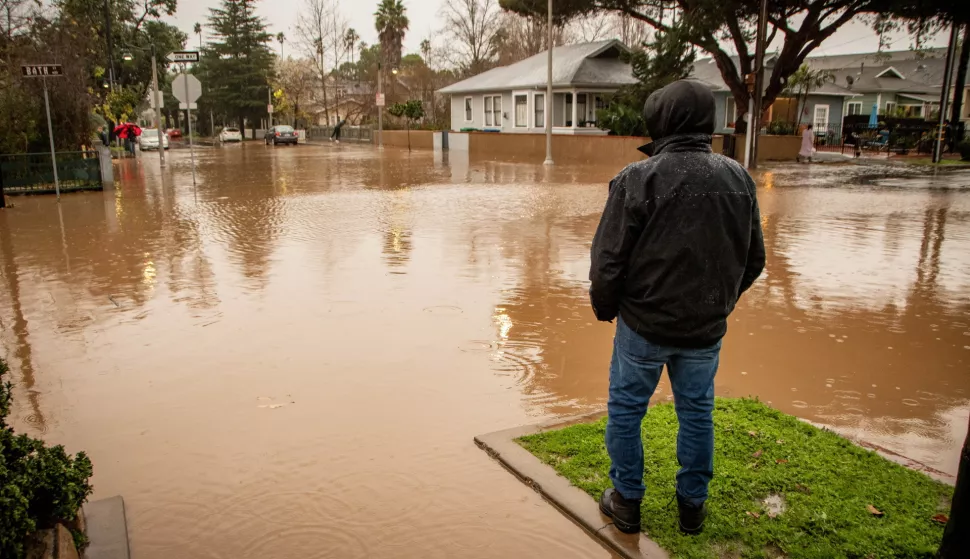 epa11127773 A man looks at the flooded intersection of Bath and Hailey streets during an atmospheric river weather event in Santa Barbara, California USA, 04 February 2024. The Weather Prediction Center has issued a rare Level 4 of 4 risk of excessive rainfall for the Santa Barbara area, with the storm also triggering flood watches for nearly 40 million people in the state of California. EPA/ERICK MADRID