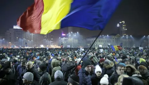 epa05763814 A Romanian man waves large-scale of the national flag as people shout anti-government slogans during a protest rally in front of government headquarters in downtown Bucharest, Romania, late 31 January 2017. Up to 12,000 people gathered in front of the government headquarters in Romania's capital to protest against a government's emergency ordinance decriminalizing official misconduct and changing the criminal law, media reported. The emergency decree was announced in the late hours of 31 January triggering a massive protest outside the government's building as protesters said that the ordinance will weaken anti-graft efforts. Another government decree would grant prison pardons for several offences, media added. EPA/ROBERT GHEMENT