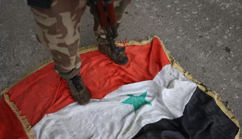 epa11762342 An opposition fighter stands on a Syrian flag as they secure the area at the Hama Airport after they took control of the city of Hama, Syria, 07 December 2024. Syrian opposition forces, led by the Islamist militant group Hayat Tahrir al-Sham (HTS), launched an offensive on 27 November, triggering counterattacks by the Syrian regime forces as well as Russian and Syrian airstrikes on opposition-controlled areas. EPA/MOHAMMED AL RIFAI