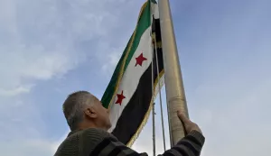 epa11769886 A man raises the Syrian opposition flag on the Syrian embassy building in Baabda, Lebanon, 11 December 2024. Syrian rebels entered Damascus on 08 December 2024 and announced the overthrow of president Bashar al-Assad. EPA/WAEL HAMZEH