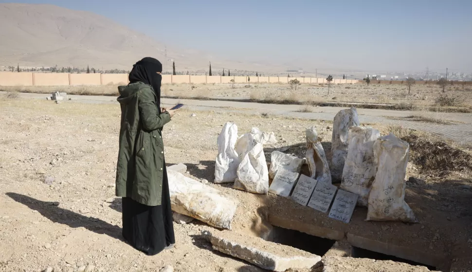 epa11784554 A woman searches for relatives in bags containing human remains at a site where a mass grave believed to contain thousands of bodies was found near the Syrian capital in Damascus, Syria, 18 December 2024. Grave sites are popping up across Syria following the ouster of former President Bashar al-Assad, who was accused of widespread extrajudicial killings. EPA/ANTONIO PEDRO SANTOS