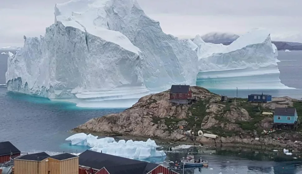 epa06885114 A general view shows an iceberg stranded near the village of Innaarsuit, in the Avannaata Municipality, northwestern Greenland, 12 July 2018 (issued 13 July 2018). The Avannaata Municipality was alarmed on 11 July, after a huge iceberg was grounded just outside the village of Innaarsuit. According to local media, police asked villagers who live closest to the water, to leave their houses over fears the iceberg could calve and affect the village with a tsunami. EPA/KARL PETERSEN DENMARK OUT