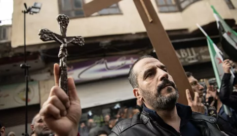 epa11791852 A protester holds a cross during a demonstration in the Bab Touma neighborhood of Damascus, Syria, 24 December 2024. Syrian Christians demonstrated against the burning of a Christmas tree overnight by masked men in the town of Suqaylabiyah in the Hama governorate.  EPA/HASAN BELAL