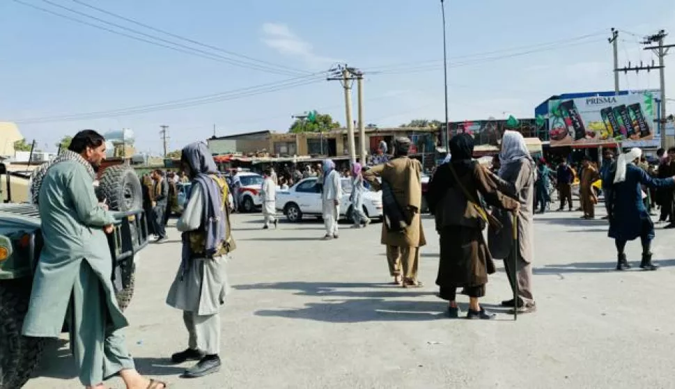 epa09421845 Taliban fighters stand guard as Afghans gather outside the Hamid Karzai International Airport to flee the country, in Kabul, Afghanistan, 20 August 2021. The Afghan interim council, formed to assist in the power transfer following President Ashraf Ghani's escape, has met several Taliban leaders to discuss issues related to control and security during the transition process. Fighting and violence have significantly reduced in Afghanistan with the surrender of the government troops and the resounding victory of the Taliban. EPA/STRINGER