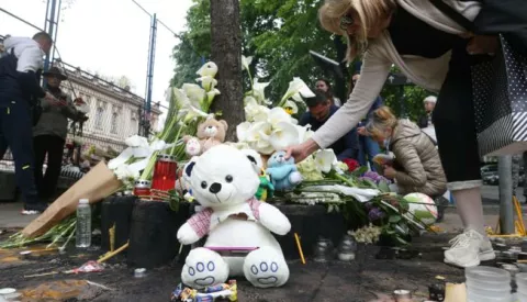 epa10608076 People leave flowers and light candles for the victims in front of the "Vladislav Ribnikar" elementary school in Belgrade, Serbia, 04 May 2023. A teenage student fatally shot seven girls and one boy using two handguns, which he had taken from his father. Six children and a teacher were also injured in the attack. EPA/ANDREJ CUKIC