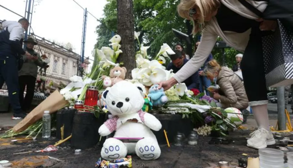 epa10608076 People leave flowers and light candles for the victims in front of the "Vladislav Ribnikar" elementary school in Belgrade, Serbia, 04 May 2023. A teenage student fatally shot seven girls and one boy using two handguns, which he had taken from his father. Six children and a teacher were also injured in the attack. EPA/ANDREJ CUKIC