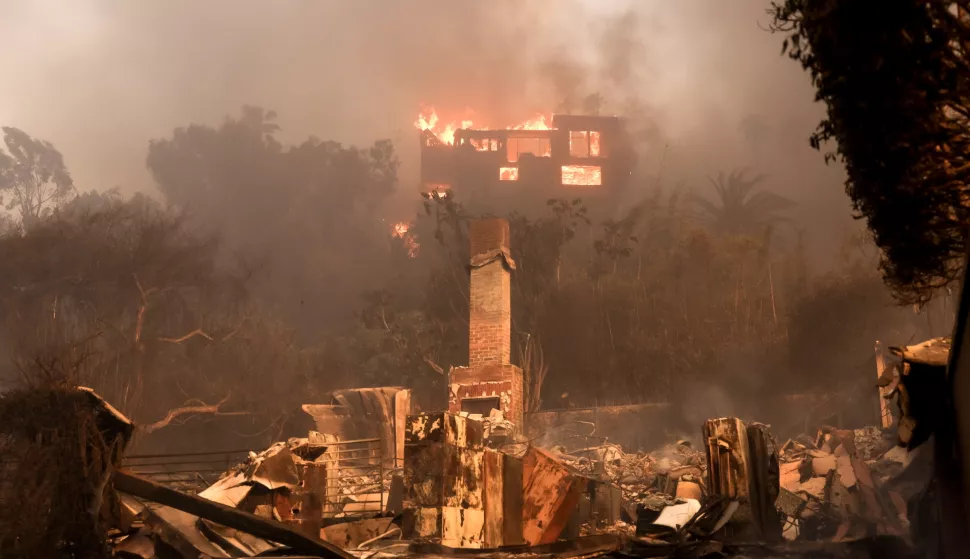 epa11813471 A house on fire and the remains of another burnt home in an area affected by the Palisades wildfire in Malibu, California, USA, 08 January 2025. According to data from California Department of Forestry and Fire Protection, CAL FIRE, the Palisades fire has burned through thousands of acres and has forced tens of thousands of evacuations in the Los Angeles area. EPA/ALLISON DINNER